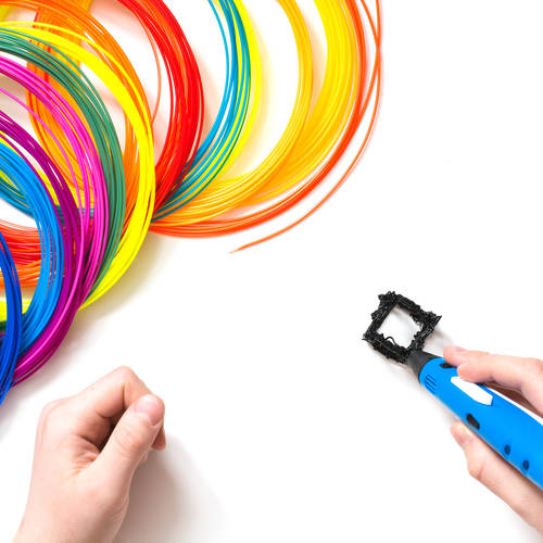Child draws 3Dpen. Colorful rainbow plastic filaments for 3D pen laying on white. New toy for child.