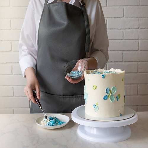 Female baker decorating tasty cake on the table