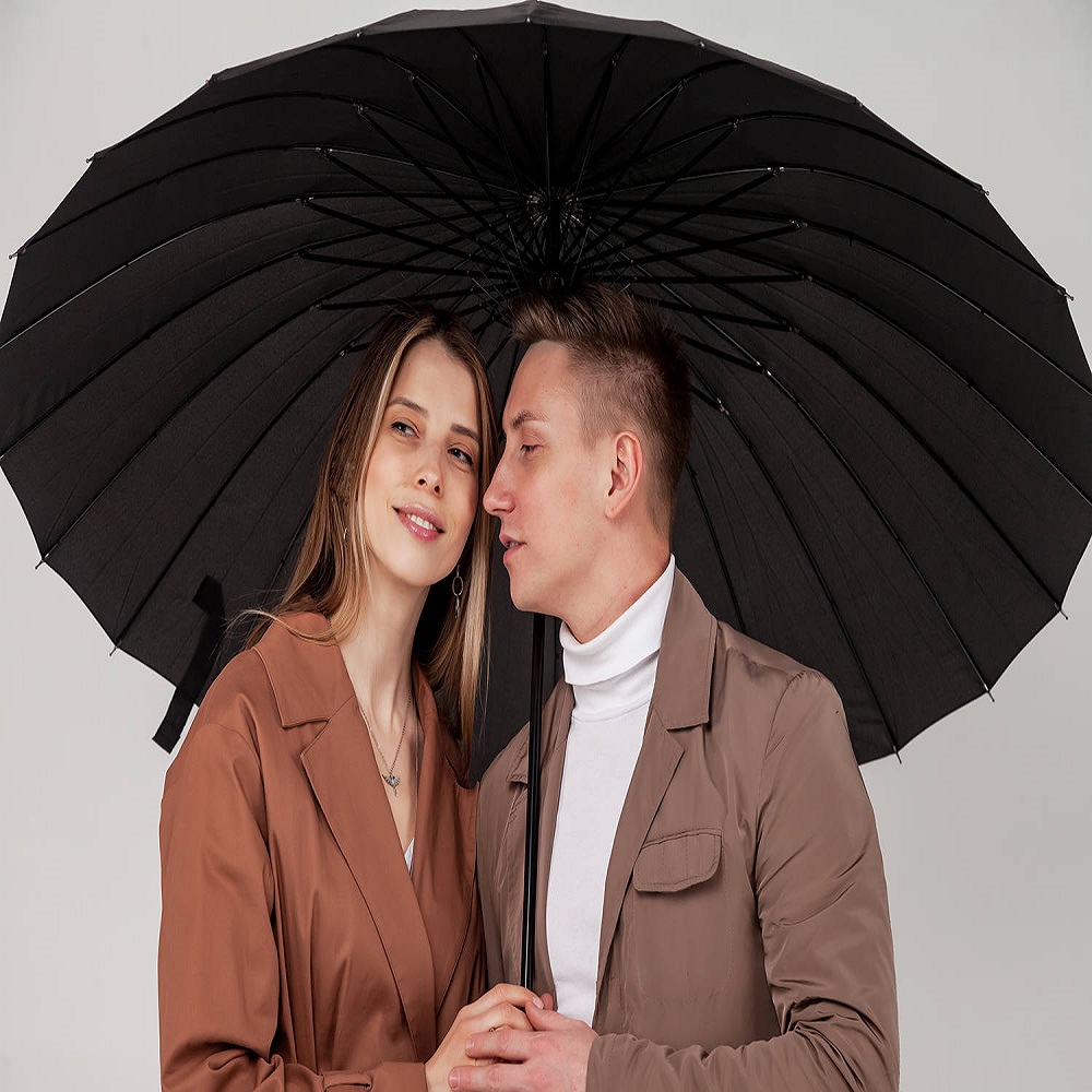 Young stylish couple with black umbrella shows love emotions